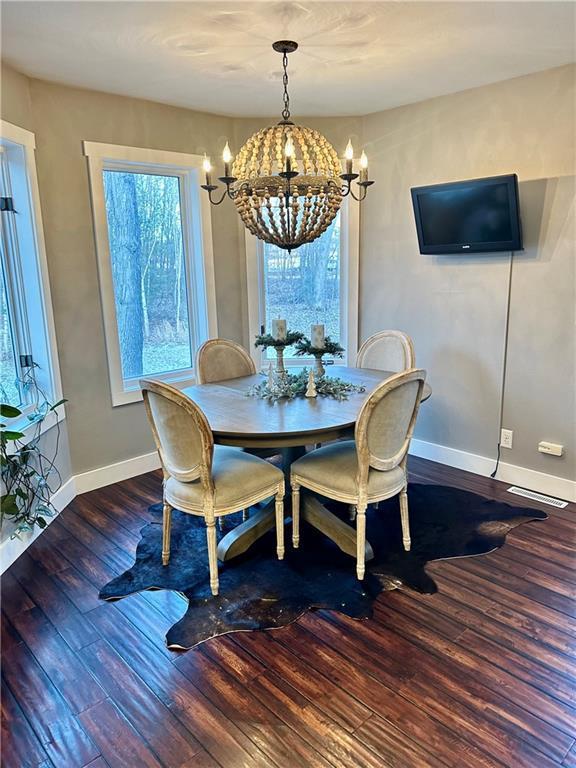 dining area with dark hardwood / wood-style flooring and an inviting chandelier