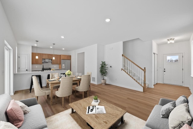 living room with a wealth of natural light, light hardwood / wood-style flooring, and sink