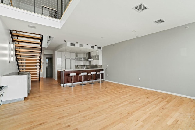 living room featuring sink, a towering ceiling, and light wood-type flooring