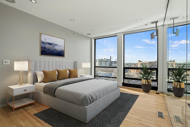 bedroom with light wood-type flooring and a wall of windows