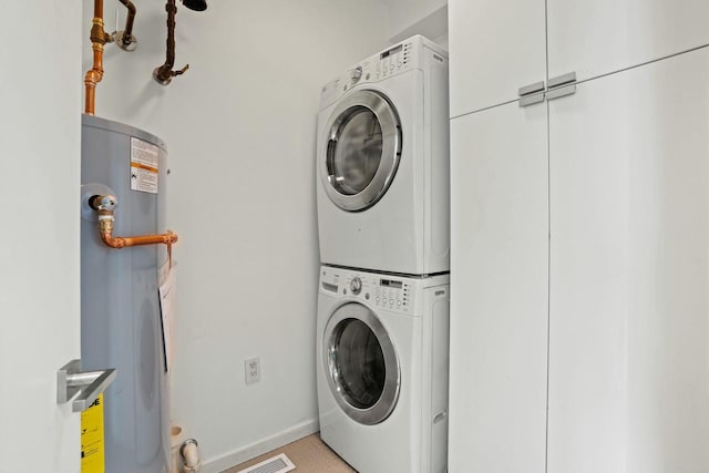 laundry area with stacked washer and dryer and water heater