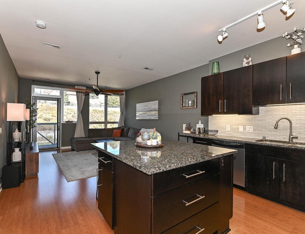 kitchen with dishwasher, a center island, sink, dark stone countertops, and dark brown cabinets