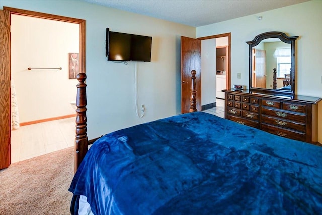 bedroom featuring a textured ceiling, light carpet, and washer / clothes dryer