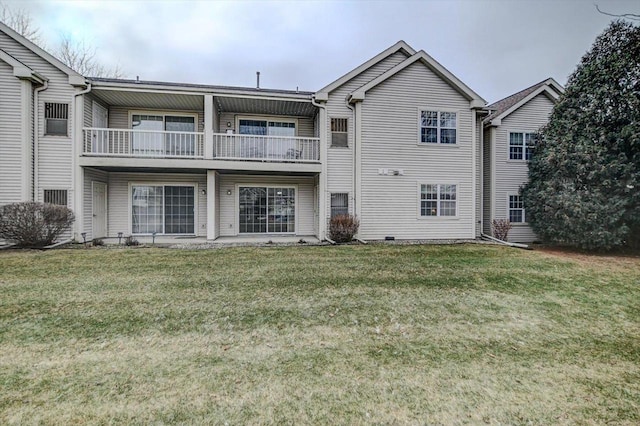 back of property featuring a balcony and a lawn