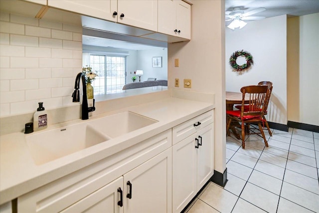 kitchen featuring white cabinets, ceiling fan, light tile patterned flooring, and sink