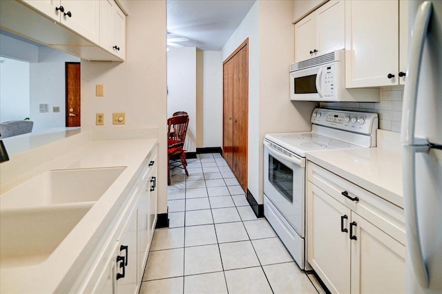 kitchen featuring sink, tasteful backsplash, white cabinets, white appliances, and light tile patterned floors