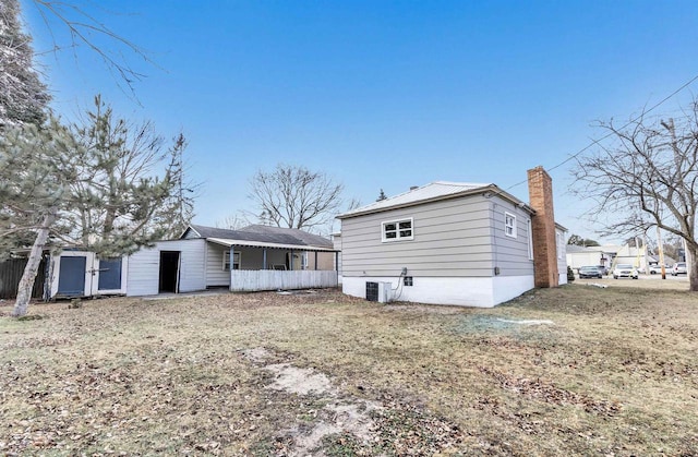 back of house with a yard and central AC