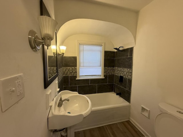 full bathroom with hardwood / wood-style floors, tiled shower / bath combo, toilet, and sink