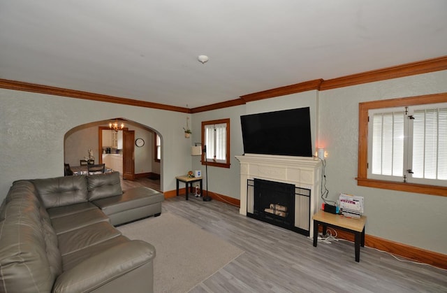 living room with a chandelier, light wood-type flooring, and ornamental molding