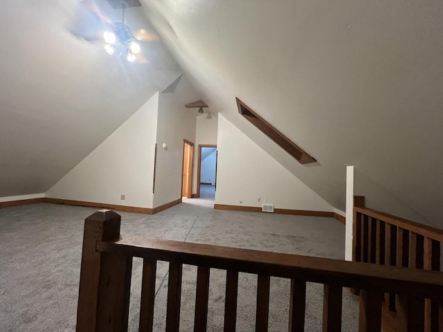 bonus room with light colored carpet, lofted ceiling with skylight, and ceiling fan