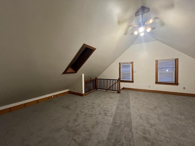 additional living space with carpet flooring, ceiling fan, and vaulted ceiling with skylight