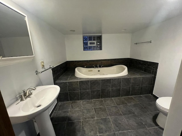 bathroom featuring tile patterned floors, tiled tub, and toilet