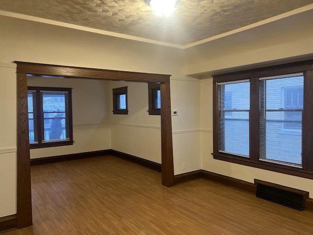 spare room with wood-type flooring, a textured ceiling, and ornamental molding