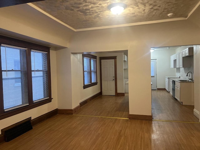 empty room with ornamental molding, sink, and dark wood-type flooring