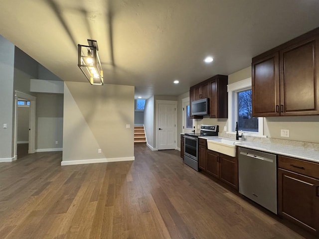 kitchen featuring appliances with stainless steel finishes, dark brown cabinetry, dark hardwood / wood-style floors, and sink