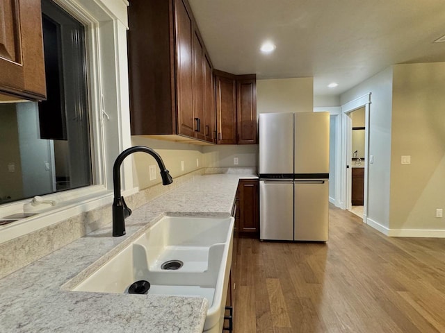 kitchen featuring stainless steel fridge, light wood-type flooring, and sink