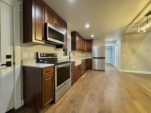 kitchen featuring dark brown cabinets, stainless steel appliances, light hardwood / wood-style floors, and sink