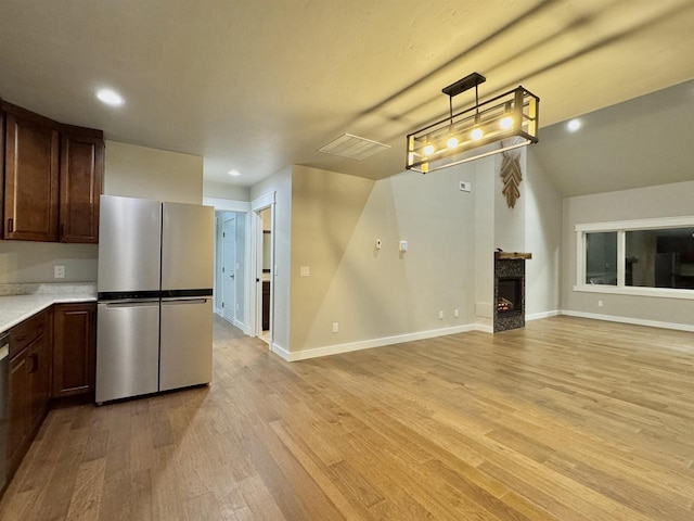 kitchen featuring decorative light fixtures, stainless steel fridge, dark brown cabinets, and light wood-type flooring