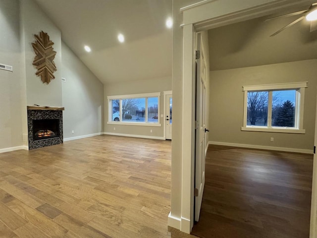 unfurnished living room with a fireplace, hardwood / wood-style floors, high vaulted ceiling, and ceiling fan