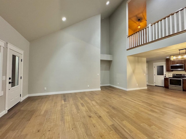 unfurnished living room featuring light wood-type flooring and high vaulted ceiling