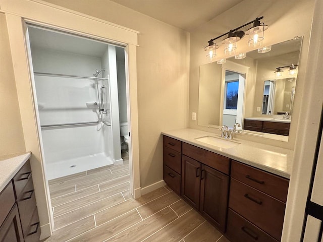 bathroom with toilet, a shower, and vanity