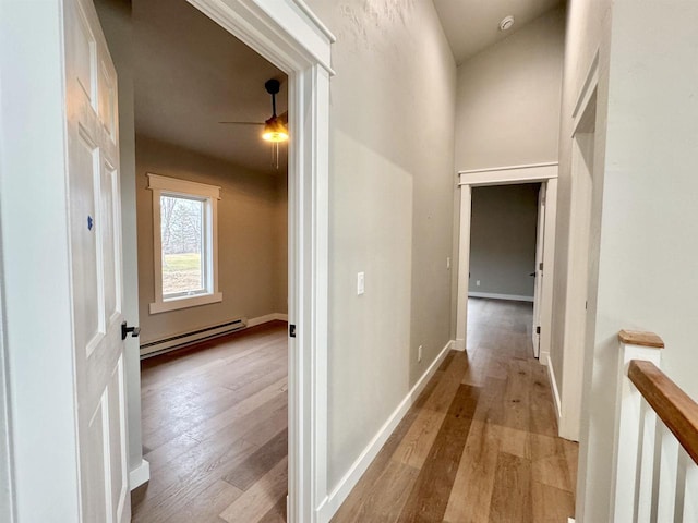 corridor with light wood-type flooring and baseboard heating