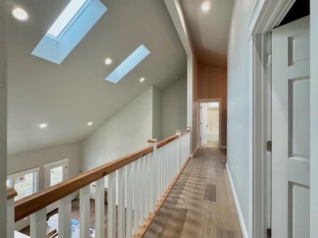 hallway featuring light hardwood / wood-style floors and vaulted ceiling with skylight