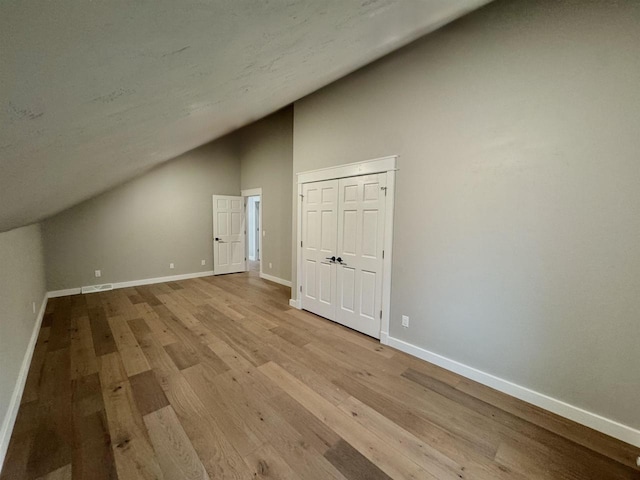 additional living space featuring light hardwood / wood-style flooring and high vaulted ceiling