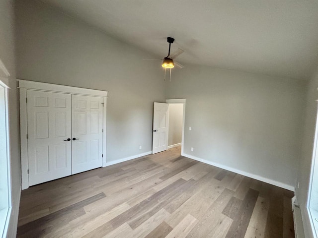 unfurnished bedroom with a closet, ceiling fan, light hardwood / wood-style flooring, and high vaulted ceiling