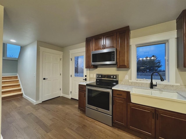 kitchen with hardwood / wood-style flooring, dark brown cabinets, sink, and appliances with stainless steel finishes