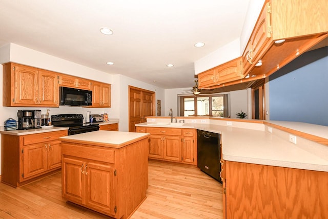 kitchen featuring sink, kitchen peninsula, light hardwood / wood-style floors, a kitchen island, and black appliances