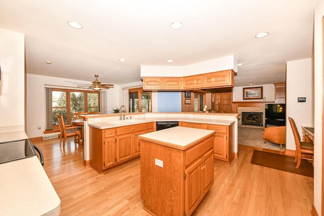 kitchen featuring a center island, sink, ceiling fan, light wood-type flooring, and kitchen peninsula