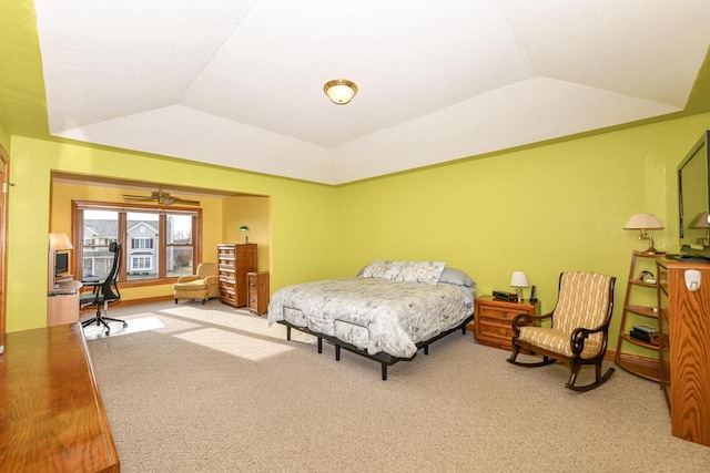 carpeted bedroom featuring a tray ceiling and vaulted ceiling