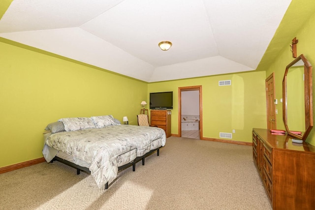 bedroom featuring light carpet, connected bathroom, a tray ceiling, and lofted ceiling