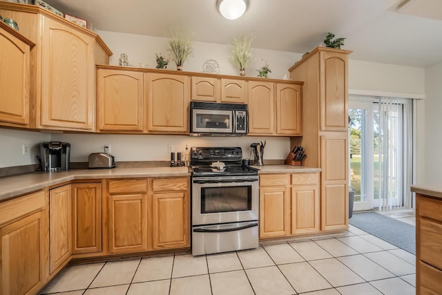 kitchen featuring light tile patterned floors, light brown cabinetry, and appliances with stainless steel finishes