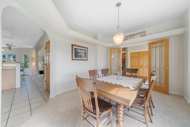 tiled dining space featuring a raised ceiling and french doors