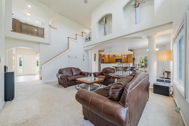 carpeted living room with a high ceiling and a baseboard heating unit