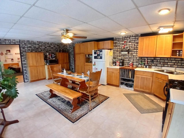 kitchen with sink, brick wall, white refrigerator, stove, and a paneled ceiling