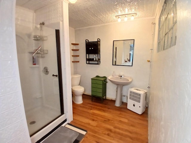 bathroom with toilet, hardwood / wood-style floors, crown molding, and a shower with shower door