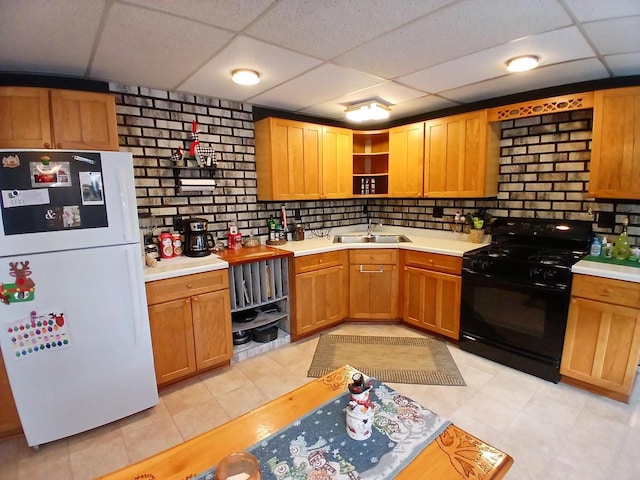 kitchen with a paneled ceiling, sink, black range with gas cooktop, and white refrigerator