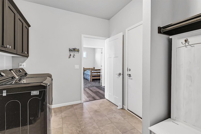 clothes washing area with washer and dryer, cabinets, and light tile patterned flooring