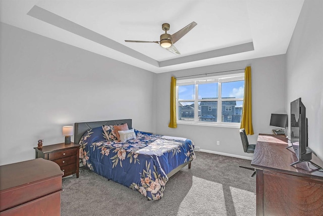 carpeted bedroom with a raised ceiling and ceiling fan