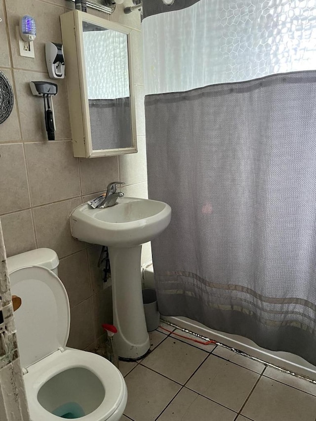 bathroom with tile patterned floors, toilet, and tile walls