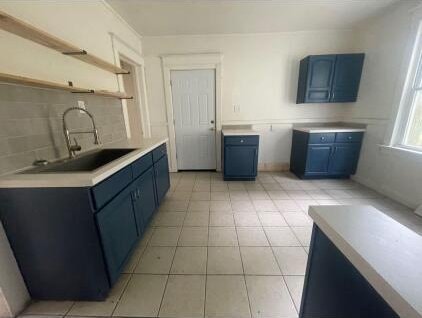 kitchen featuring blue cabinetry, tasteful backsplash, sink, and light tile patterned floors