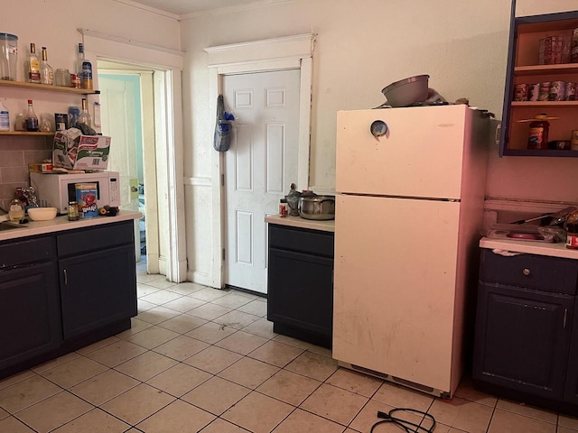 kitchen with white fridge, light tile patterned flooring, and crown molding