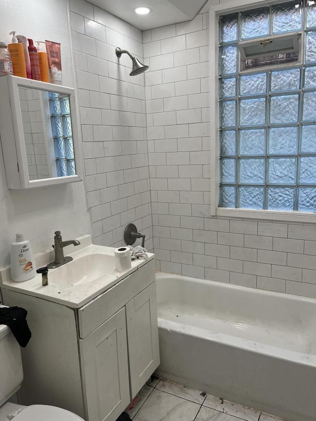 full bathroom with vanity, tiled shower / bath combo, toilet, and a healthy amount of sunlight