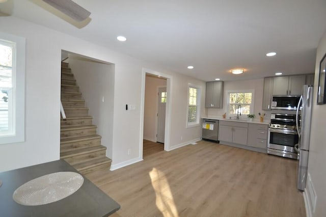 kitchen featuring appliances with stainless steel finishes, gray cabinets, light hardwood / wood-style floors, and sink