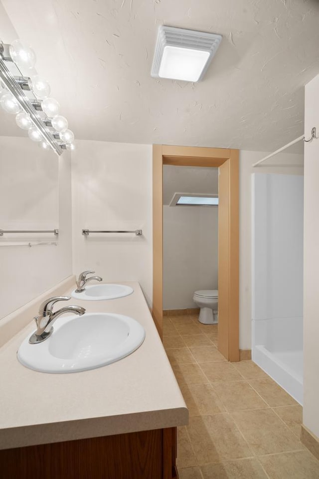 bathroom with tile patterned flooring, vanity, toilet, and walk in shower