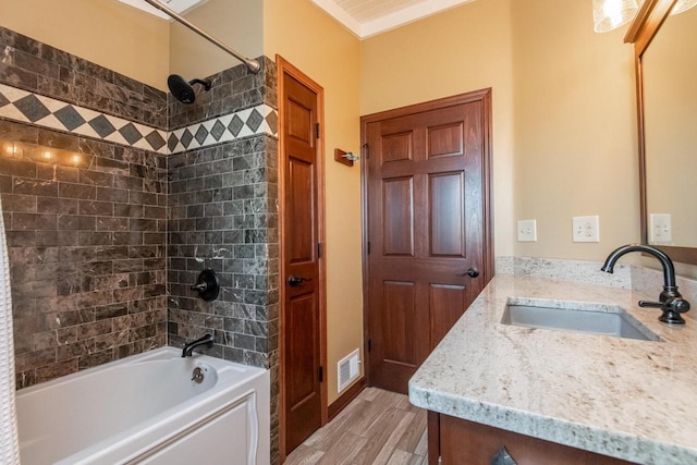 bathroom featuring hardwood / wood-style flooring, vanity, and tiled shower / bath