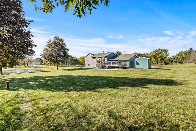 view of yard featuring a deck with water view and a storage shed